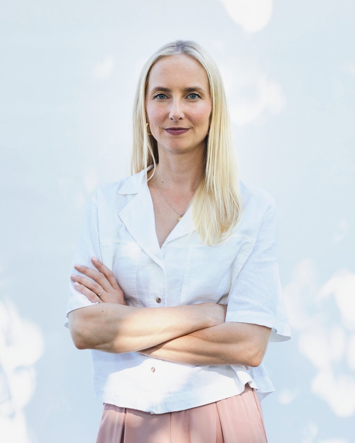Katarina Blom med armarna i kors, lugn och självsäker, i vit linneskjorta